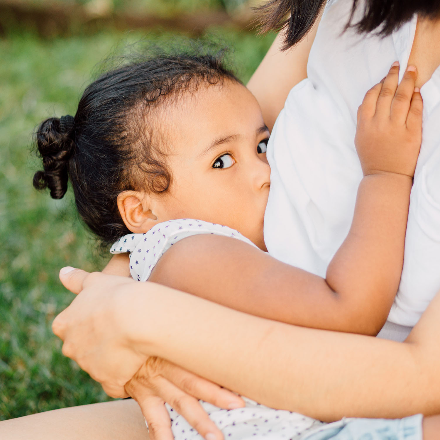 Uma mãe segurando sua filha no colo enquanto a amamenta