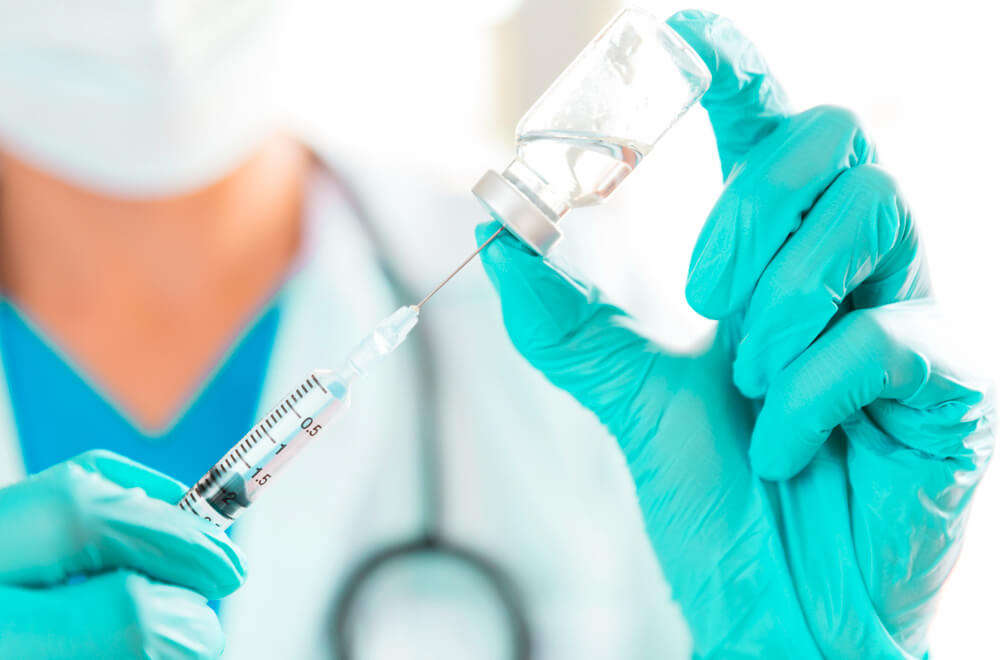 Enfermeira coloca o líquido da vacina dtpa na injeção.