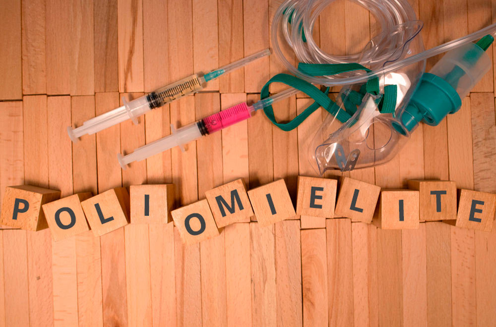 uma imagem com um fundo de madeira e em cima tem duas seringas e cubos escrito a palavra poliomielite