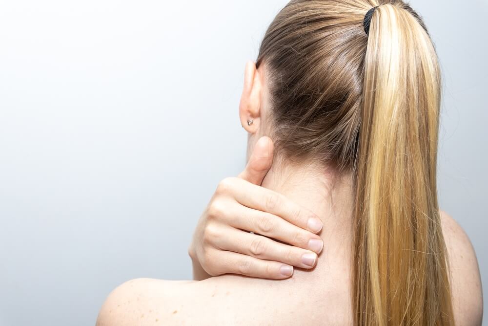 Mulher com meningite pneumocócica sentindo rigidez no pescoço.