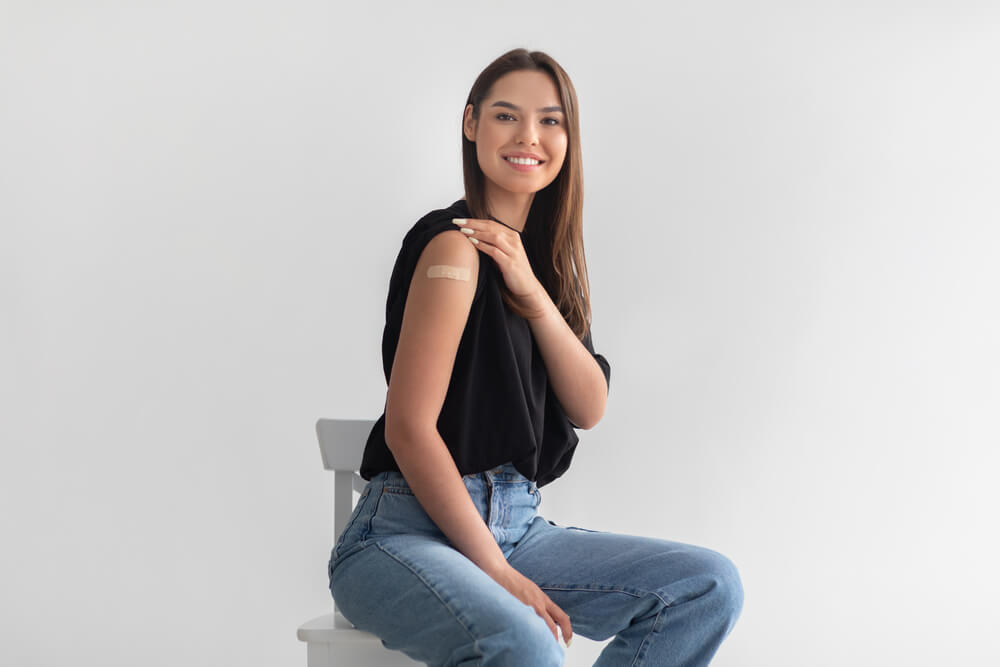 Mulher mostrando o adesivo após a vacinação com Gardasil